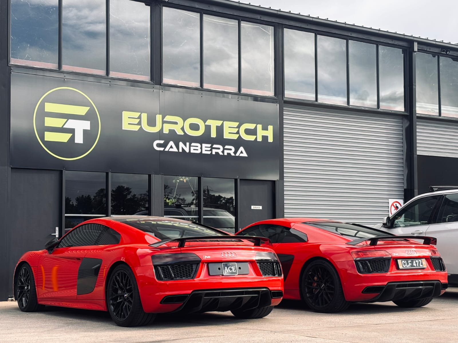 Two red Audi R8 sports cars parked outside Eurotech Canberra, a high-performance automotive service centre, showcasing the company's expertise in European car care.